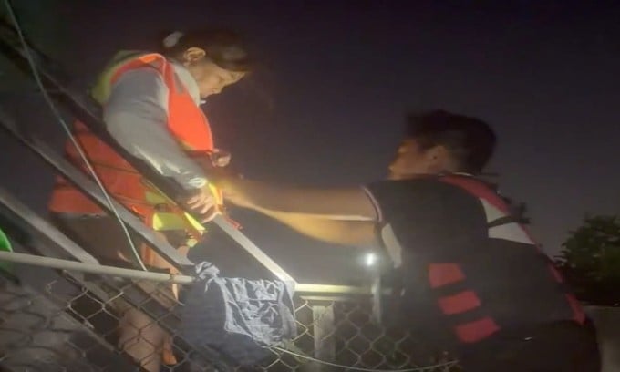 Đội của anh Phong lái cano vào vùng ngập sâu ở ven sông Phú Hài, cứu người phụ nữ mắc kẹt trên mái nhà. Ảnh: Minh Bằng